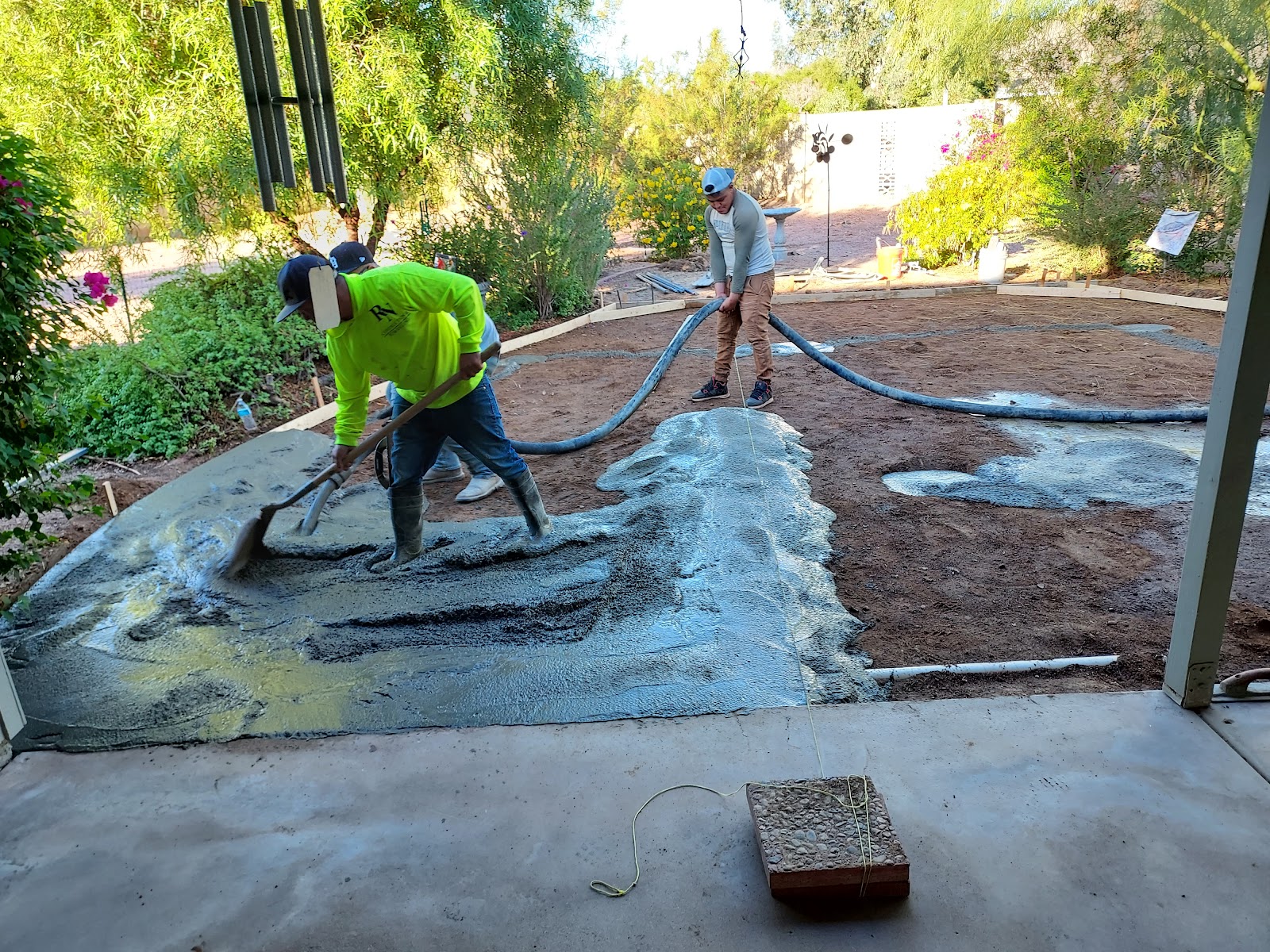 Crew finishing a wet concrete pour in a Phoenix backyard
